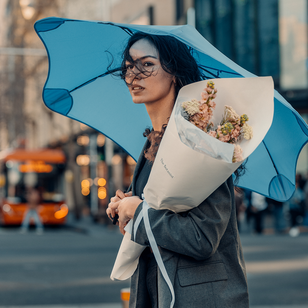 Woman holding flowers and blue metro blunt umbrella